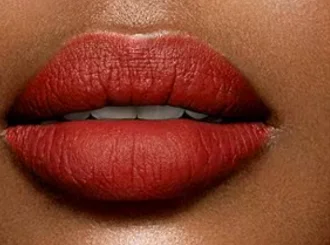 Lancôme 196 French Touch, a brick red lipstick, on lips